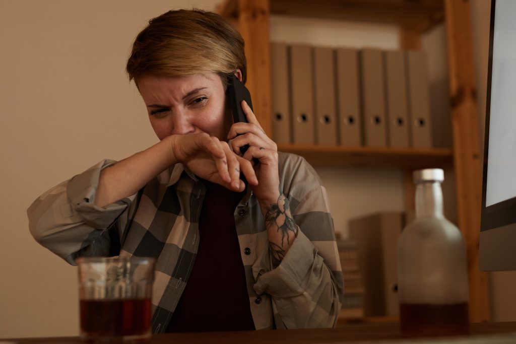 Person contemplating a phone call, symbolizing the importance of reaching out to an addiction hotline for help.