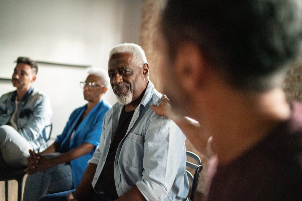 A diverse group of individuals sharing their experiences in a support group setting