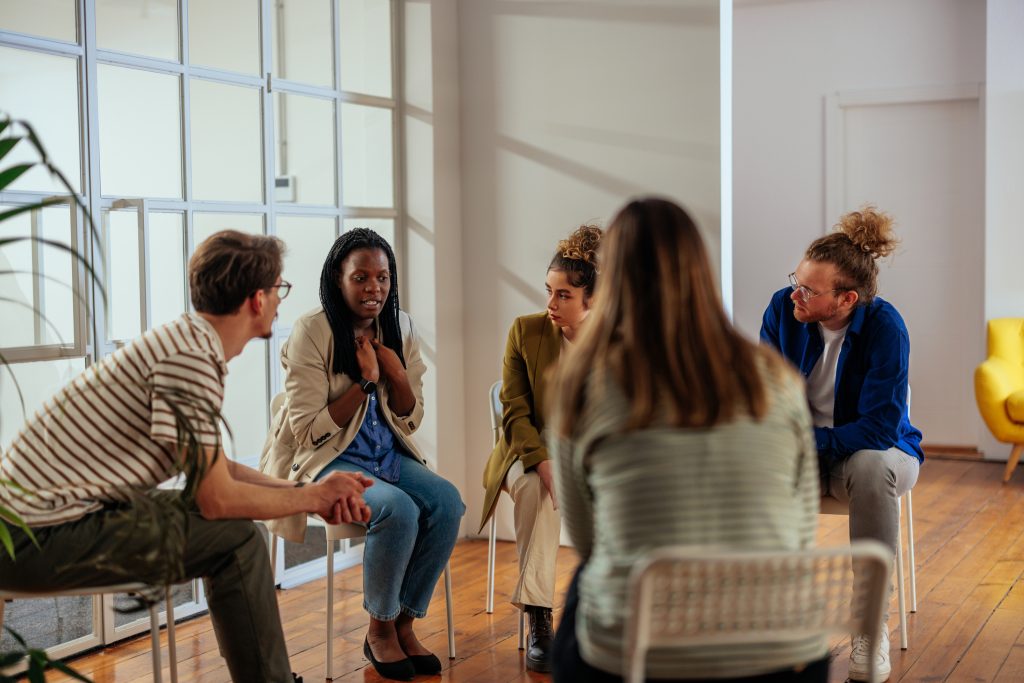 A diverse group of people discussing various treatment approaches for addiction recovery