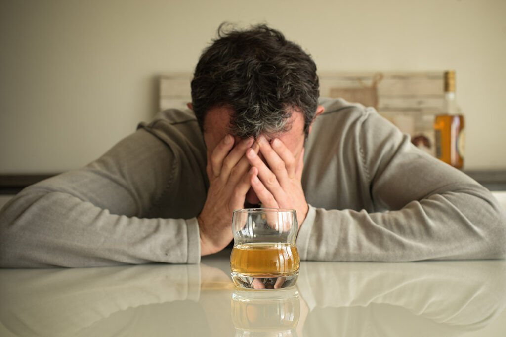 A glass of alcohol with addiction warning signs, symbolizing the dangers of alcohol dependence.