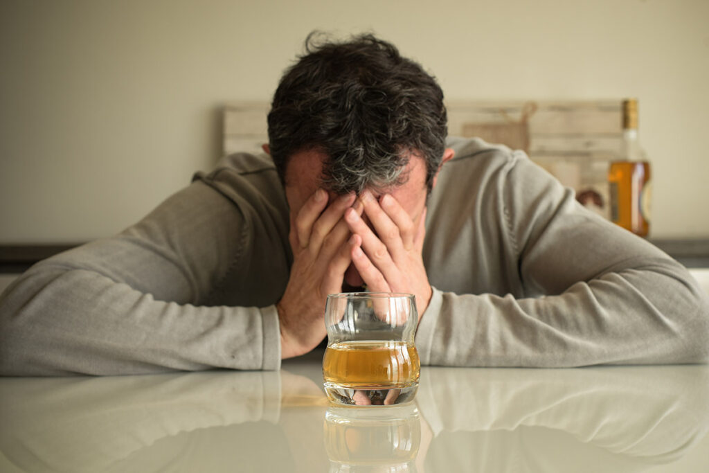 A glass of alcohol with addiction warning signs, symbolizing the dangers of alcohol dependence.