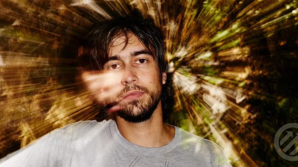 Alex G performing live on stage with a guitar, known for his introspective indie music and abstract lyrics.